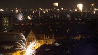 01.01.2023, Nordrhein-Westfalen, Bielefeld: Silvesterfeuerwerk ist zum Jahreswechsel über der Kulisse der Stadt zu sehen