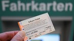 Ein 9-Euro-Ticket für Juli 2022 wird am Hauptbahnhof vor dem Wort "Fahrkarten" hochgehalten