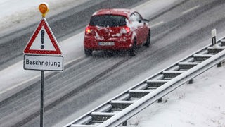 Ein Auto fährt an einem Verkehrsschild mit der Aufschrift ·Beschneiung· vorbei.