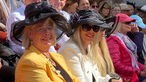 Hut tragende Frauen auf der Tribüne bei der Königsparade in Neuss