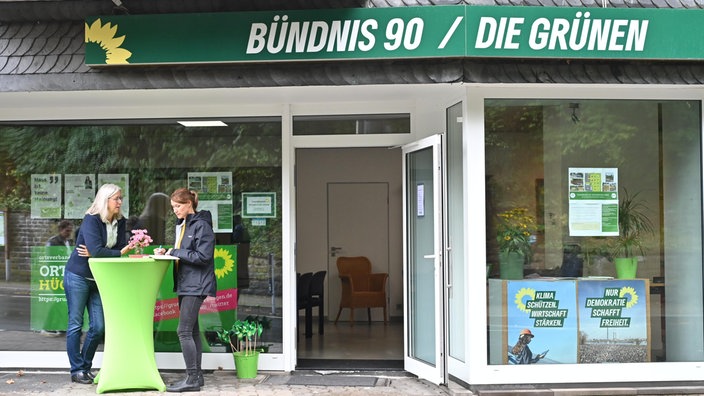 Zwei Menschen unterhalten sich vor einem Büro der Partei Bündnis 90 / Die Grünen