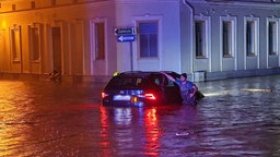 Hochwasser in Österreich - Ein Auto steht auf einer überfluteten Straße