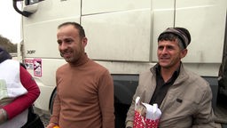 Zwei LKW-Fahrer erhalten Geschenktüten und freuen sich.