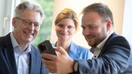 Achim Post, Sarah Philipp und Frederick Cordes machen ein gemeinsames Selfie mit dem Smartphone.