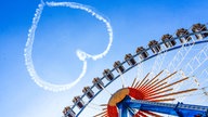 Zum Beginn des Oktoberfests 2023 steht ein Herz am Himmel vor dem Riesenrad.