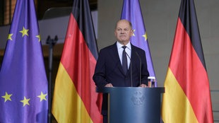 Olaf Scholz vor der Fahne der Europäischen Union