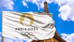 Die Flagge der Olympische Spiele 2024, im Hintergrund der Eiffelturm