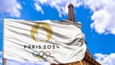 Die Flagge der Olympische Spiele 2024, im Hintergrund der Eiffelturm