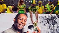 ein brasilianischer Fan hält vor dem Spiel eine nachgebildete WM-Trophäe über das Bild des ehemaligen Spielers Pelé