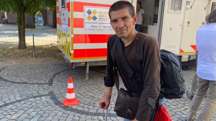 Patient Fred mit Krücken vor dem Pflastermobil in Mönchengladbach
