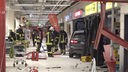 Einsatzkräfte der Feuerwehr stehen neben dem Unfallsauto, welches eine Schneise der Verwüstung im Supermarkt-Einkaufszentrum hinterlassen hat