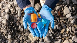 Plastikdeckel aus der Umwelt in einer Hand