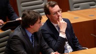 Marcus Optendrenk (CDU, l), Minister der Finanzen NRWs, und Hendrik Wüst (CDU), Ministerpräsident von NRW, sitzen bei einer Plenarsitzung im NRW-Landtag
