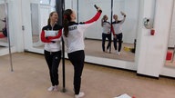 Zwei Freundinnen stehen im Trainingsanzug im Pole-Studio und machen ein Selfie