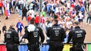 Einsatzkräfte der Polizei stehen vor dem Stadion während die Fans zum Spiel kommen