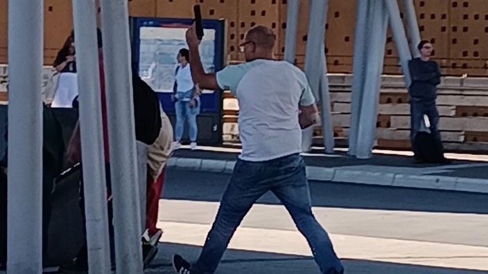 Ein Mann mit erhobener Waffe im Wuppertaler Hauptbahnhof