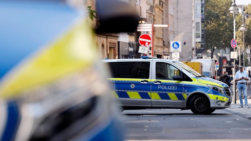 Zwei Polizeiwagen stehen vor einem Modegeschäft auf der Ehrenstraße nahe der Kölner Ringe im September.