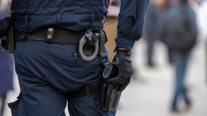 Ein Polizist hat seine Hand an seiner Waffe. 
