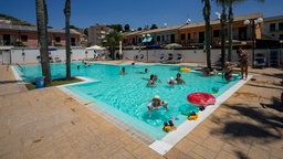 Urlauber schwimmen im Pool eines Hotels in Sizilien