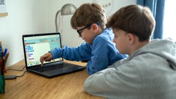 Zwei Jungs vor einem Laptop mit "Programmieren mit der Maus"