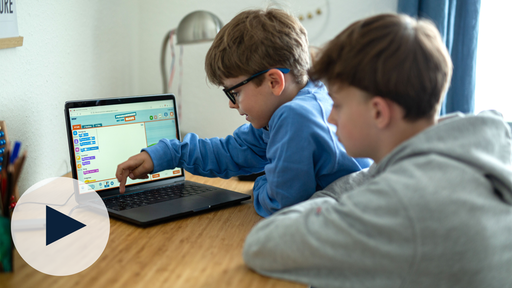 Zwei Jungs sitzen vor einem Computer mit "Programmieren mit der Maus