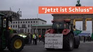 Ein Traktor mir einem großen Banner hinten steht vor dem Berliner Tor; auf rotem Banner in weißer Schrift "Jetzt ist Schluss"