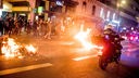 Ein Feuer brennt auf einer Straße während Menschen nach der Verabschiedung einer umstrittenen Rentenreform protestieren und die Polizei im Einsatz ist.