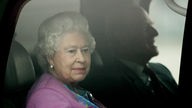 Queen Elizabeth II. sitzt in rosa Kostüm in einem Auto und schaut aus dem Fenster.