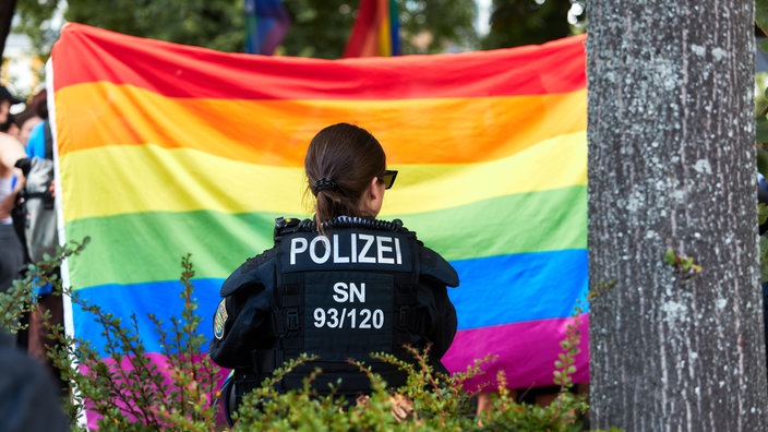 Polizisten steht vor einer Regenbogenflagge