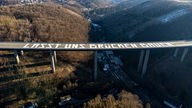 Die Luftaufnahme zeigt die riesige Friedensbotschaft «Lasst uns Brücken bauen» auf der gesperrten Rahmedetal-Brücke der Autobahn 45 bei Lüdenscheid (Nordrhein-Westfalen).
