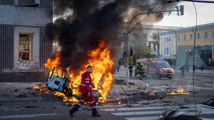  Ein Sanitäter geht an einem brennenden Auto nach einem russischen Angriff vorbei.