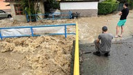 Anwohner und Touristen filmen einen über die Ufer getretenen Bach in Ika. Stundenlanger Starkregen und Gewitter haben viele Straßen in der bei Urlaubern beliebten Region unpassierbar gemacht. 