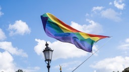 Regenbogenflagge im Wind: leicht bewölkter Himmel