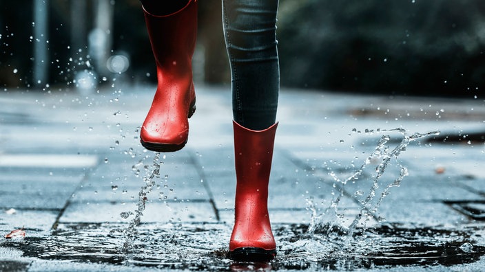 Rote Regenstiefel in einer Pfütze