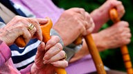 Seniorinnen sitzen auf einer Parkbank und halten ihre Gehstöcken.