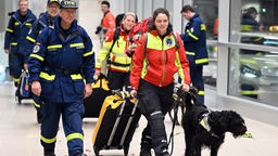Rettungskräfte werden von jubelnden Menschen auf dem Flughafen in Köln begrüßt. Mehrere Such- und Rettungsteams aus Deutschland sind nach tagelangem Einsatz im Erdbebengebiet der Türkei in die Heimat zurückgekehrt.