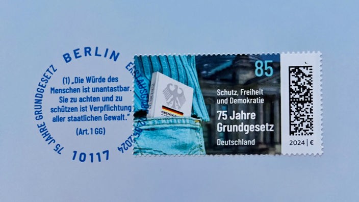 Briefmarke mit der Aufschrift "75 Jahre Grundgesetz" mit einem Stempel, der Artikel 1 im Grundgesetz zitiert
