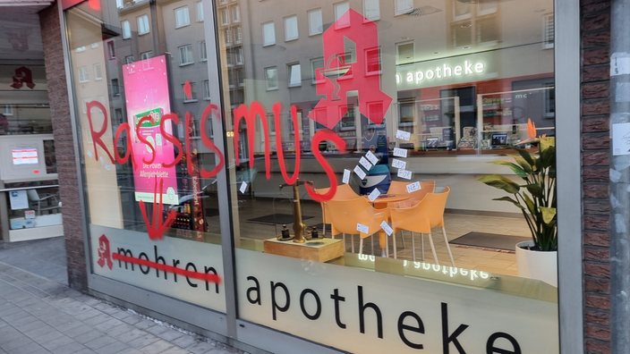 Das Schaufenster der Mohrenapotheke in Wuppertal-Barmen. Das Wort "mohren" wurde durchgestrichen und das Wort "Rassismus" wurde groß und in roter Farbe an die Scheibe gesprüht.