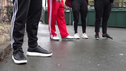 Vier Jugendliche stehen in einer Reihe und tragen jeweils eine Jogginghose.