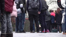 Kinder stehen auf dem Schulhof und einige tragen eine Jogginghose.