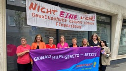 Mitglieder des NRW Netzwerks gegen Gewalt an Frauen demonstrieren mit einem Plakat