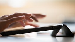 Zwei Hände tippen auf einem Tablet - Symbolbild zum digitalen Lernen
