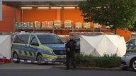 Ein Polizist bewacht einen Tatort vor einem Aachener Baumarkt