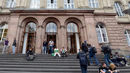 Studierende sitzen auf der Treppe am Eingang zum Hauptgebäude der RWTH Aachen.