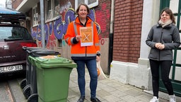 Anja Maul hält einen Hinweis zu Plastikbeuteln in Biotonnen in die Kamera