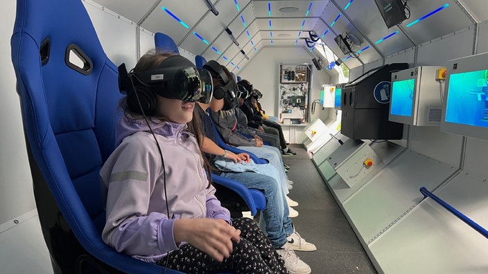 Mehrere Schüler mit einer VR-Brille sitzen im Spacebuzz One