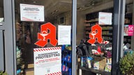 Apothekeneingang mit zwei großen A-Symbolen und einem Protestplakat