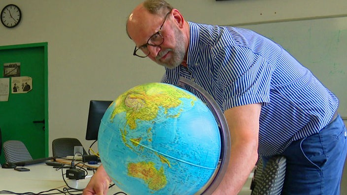 Astrophysiker der Uni Wuppertal schaut sich den Globus an.