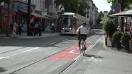 Eine Fahrradfahrerin kreuzt Straßenbahngleise. Die Rheinbahn in Düsseldorf hat ein Gleis verbaut, das Fahrradfahrer vor Unfällen schützen soll.