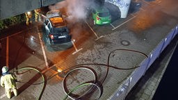 Zwei brennende Fahrzeuge auf einem Parkplatz